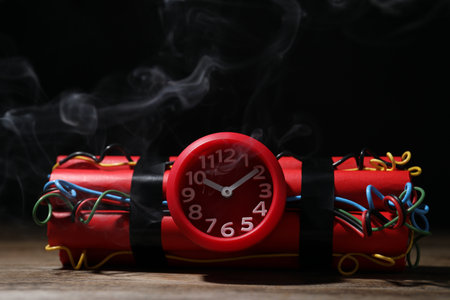 Dynamite time bomb on wooden table against black background