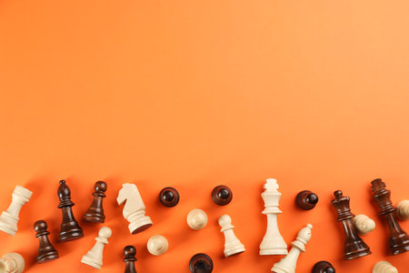 Chess pieces on orange background, flat lay with space for text. board game componentsの写真素材
