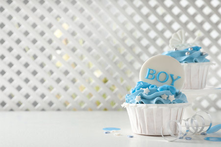 Delicious cupcakes with light blue cream and toppers on white table, space for text. baby shower partyの写真素材