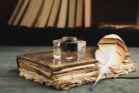 Feather pen, inkwell and book on blue wooden tableの写真素材