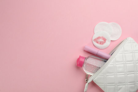 Clean and dirty cotton pads, cleansing water with mascara in bag on light pink background, flat lay. Space for textの写真素材