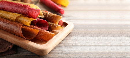 Delicious fruit leather rolls on wooden table, closeupの写真素材