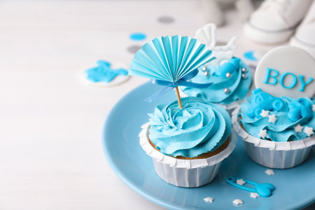 Delicious cupcakes with light blue cream and toppers for baby shower on white wooden tableの写真素材