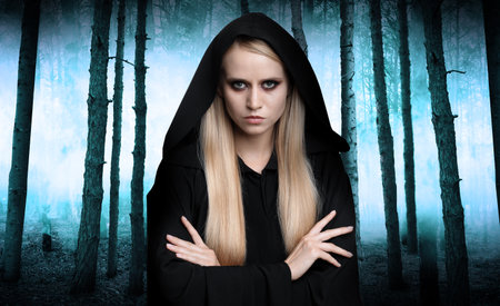 Witch wearing black mantle in foggy forest. scary fantasy character
