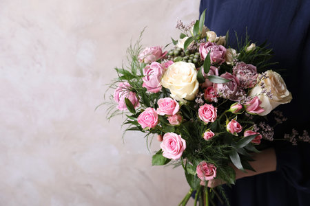 Woman with bouquet of beautiful roses on beige background, closeup. Space for textの写真素材