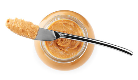 Glass jar and knife with tasty peanut butter on white background, top viewの写真素材