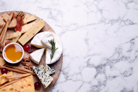 Cheese plate with honey, grapes and nuts on white marble table, top view. Space for textの写真素材