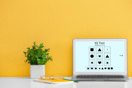 Modern laptop with IQ test on screen near yellow wallの写真素材