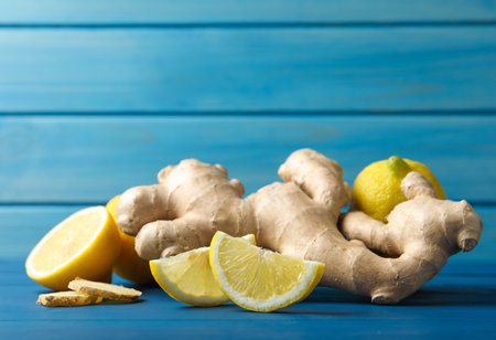 Fresh lemons and ginger on blue wooden table. Space for text