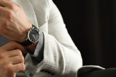 Businessman with luxury wrist watch on black background, closeupの写真素材