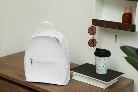 Stylish urban backpack on wooden chest of drawers in hallwayの写真素材