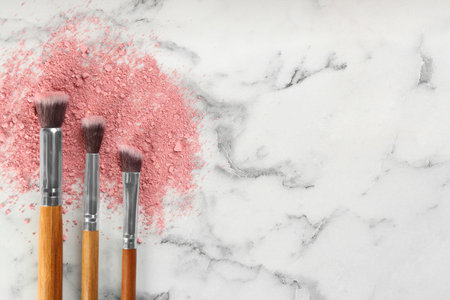 Makeup brushes and scattered eye shadow on white marble table, flat lay. Space for textの写真素材