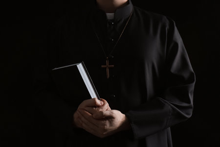 Priest with Bible on dark background, closeupの写真素材