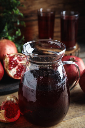 Jug of pomegranate juice and fresh fruits on wooden tableの写真素材