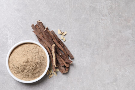 Dried sticks of liquorice root and powder on grey table, flat lay. Space for textの写真素材