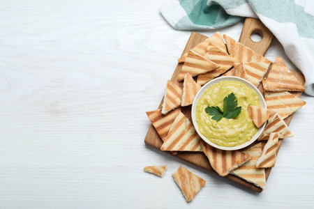 Delicious pita chips and hummus on white wooden table, flat lay. Space for textの写真素材