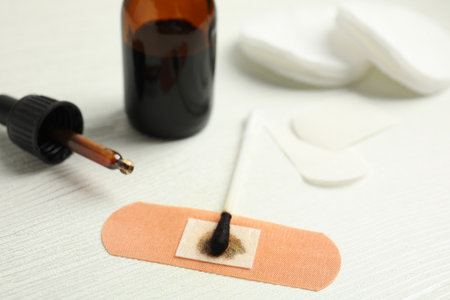 Cotton bud with medical iodine and sticking plaster on white wooden table, closeupの写真素材