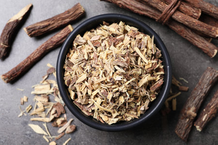 Dried sticks of liquorice root and shavings on grey table, flat layの写真素材