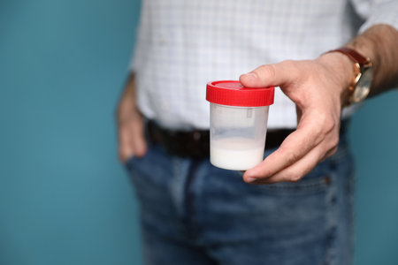 Donor holding container with sperm on turquoise background, closeup. Space for textの写真素材