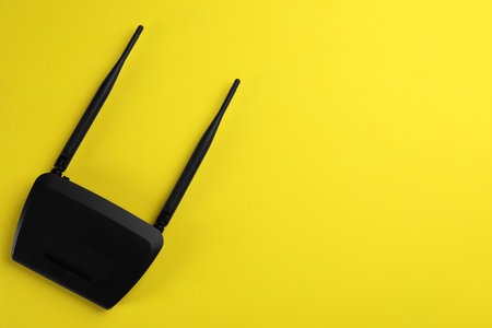 Modern WiFi router on yellow background, top view. Space for textの写真素材