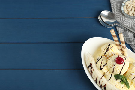 Delicious dessert with banana ice cream on blue wooden table, flat lay. Space for textの写真素材