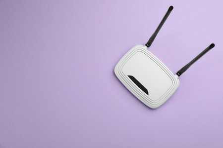 Modern WiFi router on lilac background, top view. Space for textの写真素材