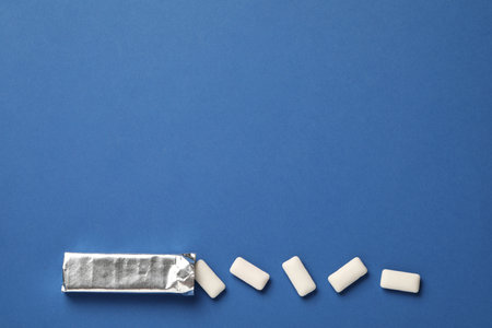 Pack and chewing gum pieces on blue background, flat lay. Space for textの写真素材