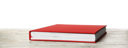 Book with red cover on wooden table against white backgroundの写真素材