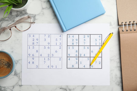 Sudoku, pen, planner, glasses and cup of coffee on white marble table, flat layの写真素材