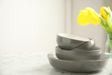 Set of clean dishware and flowers on white marble table. Space for textの写真素材