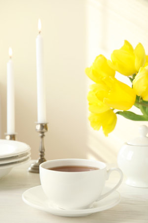 Tea set, candles and flowers on white wooden tableの写真素材