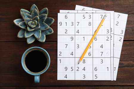 Sudoku, pencil, cup of coffee and decorative succulent on wooden table, flat layの写真素材