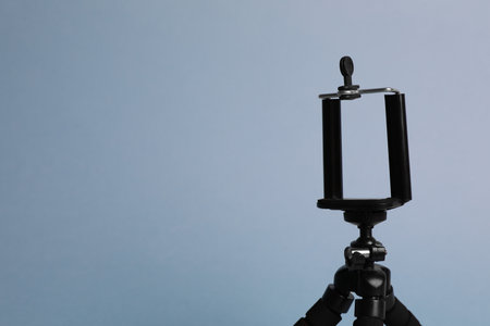 Modern stylish mobile tripod on light blue background. Space for textの写真素材