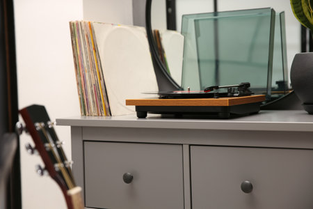 Stylish turntable with vinyl record on chest of drawers indoorsの写真素材