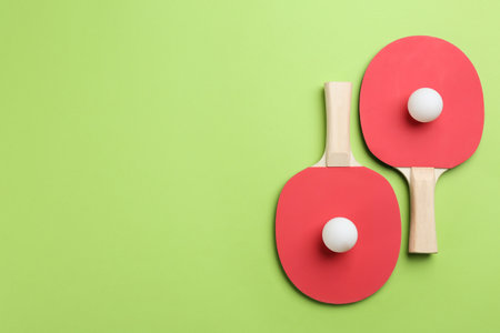rackets and balls on green background, flat lay. Space for textの写真素材