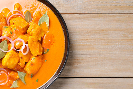Delicious chicken curry in pan on wooden table, top view. Space for textの写真素材