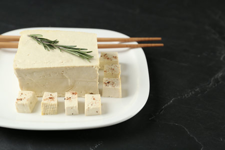 Pieces of delicious tofu with rosemary on black table. Soybean curdの写真素材