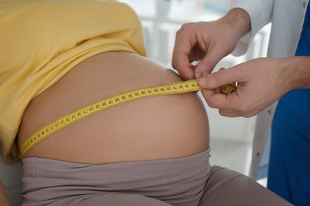 Doctor measuring pregnant woman's belly with tape in clinic, closeupの写真素材