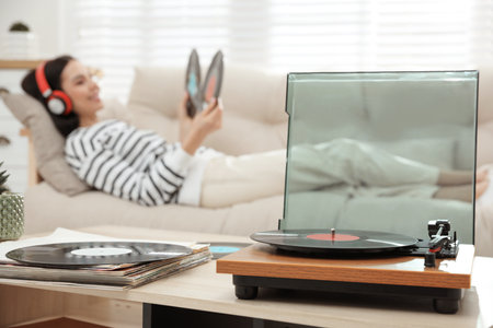 Woman listening to music with turntable in living roomの写真素材