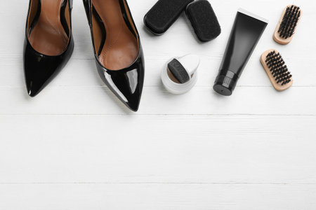 Flat lay composition with shoe care accessories and footwear on white wooden background. Space for textの写真素材