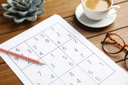 Sudoku, pencil, eyeglasses and cup of coffee on wooden tableの写真素材