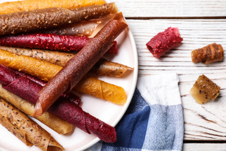 Delicious fruit leather rolls on white wooden table, flat layの写真素材