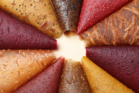 Delicious fruit leather rolls on beige background, closeup