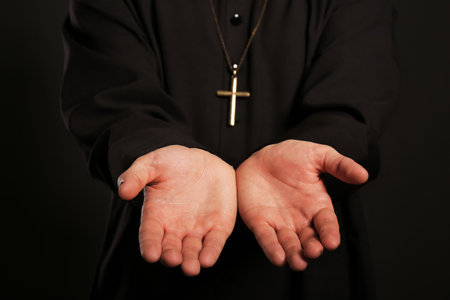 Priest reaching out his hands on black background, closeupの写真素材