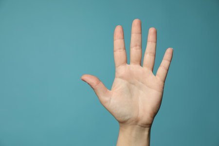 Left-handed woman holding open palm on light blue background, closeup. Space for textの写真素材