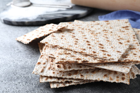 Stack of traditional matzos on gray table, closeup