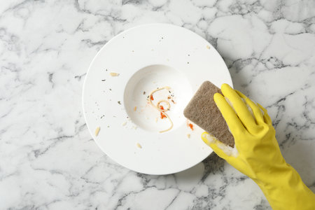 Woman washing dirty plate at white marble table, top viewの写真素材