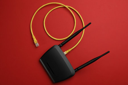 Modern Wi-Fi router with cable on red background, top viewの写真素材