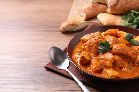Bowl of delicious chicken curry on wooden table, space for textの写真素材