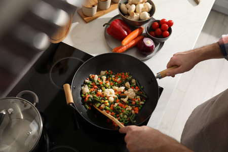 Man stirring mix of fresh vegetables in frying pan, above viewの写真素材